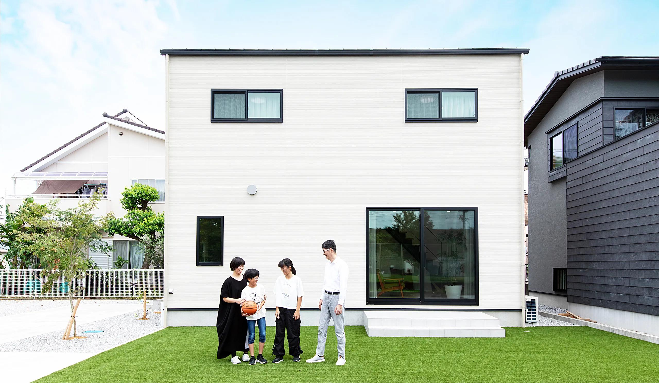 親子3人で家の前で手を繋いでいる