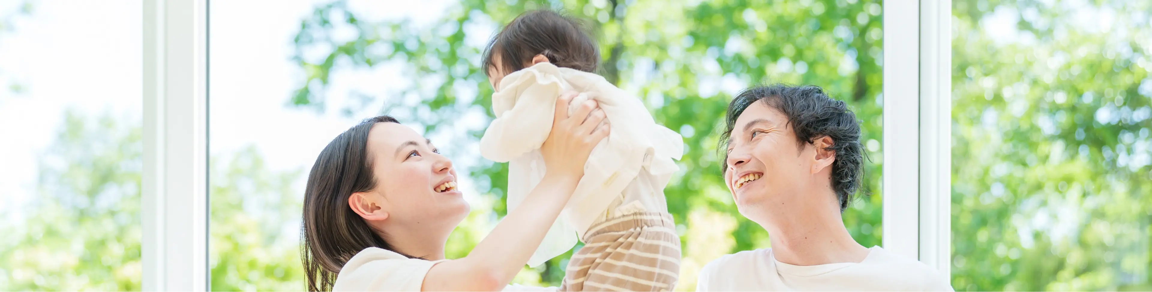 お母さんが子供を抱き上げ、お父さんが微笑んでいる